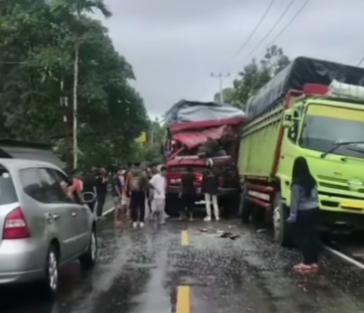 Truk merah menabrak truk hijau yang sedang parkir hingga mengalami kerusakan parah