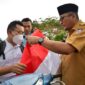 Wali Kota Padang Hendri Septa saat membagikan bendera merah putih kepada pengendara yang melintas di depan Kantor Balaikota, Selasa (2/8). Foto: Dinas Kominfo Kota Padang