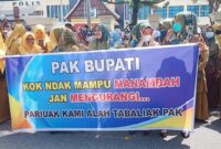 Perangkat nagari yang berdemonstrasi di depan Halaman Kantor Bupati Pesisir Selatan sambil membawa spanduk yang bertuliskan