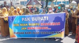 Perangkat nagari yang berdemonstrasi di depan Halaman Kantor Bupati Pesisir Selatan sambil membawa spanduk yang bertuliskan 