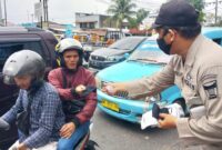 Petugas saat membagikan masker kepada pengendara 