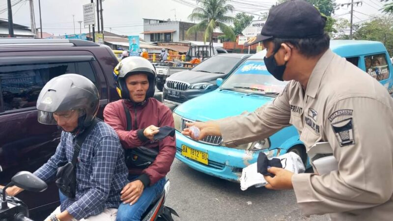 Petugas saat membagikan masker kepada pengendara 