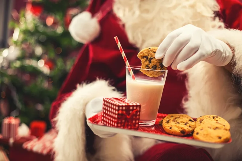 
<p>Kue dan susu untuk Santa dan wortel untuk rusa kutub tertinggal di atas meja di depan api yang menyala dan pohon Natal yang menyala.

